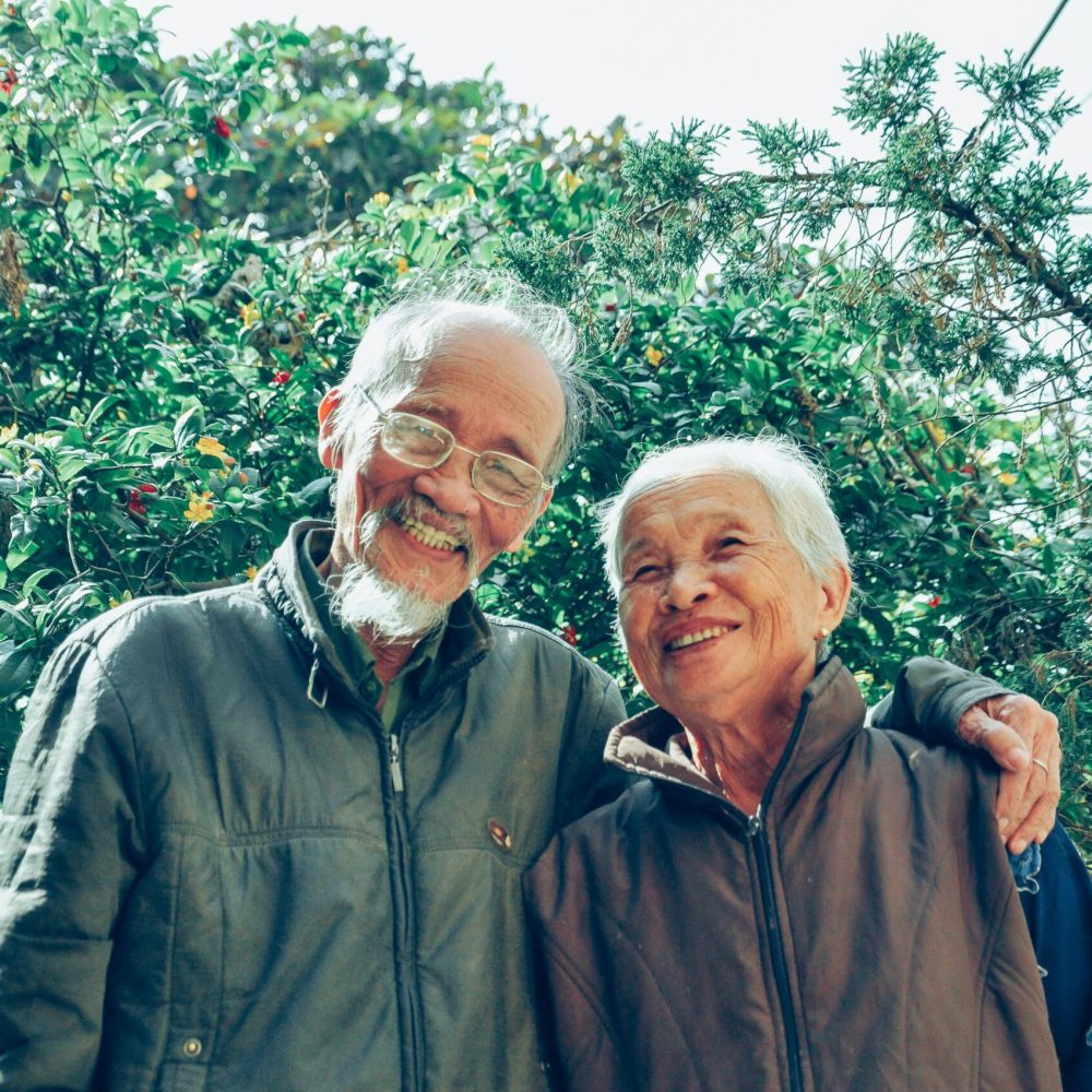 Senior couple enjoying a joyful moment together in a lush garden setting, exuding love and happiness.